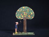 une petite figurine représentant un homme debout près d'un arbre chargé d'oranges