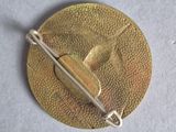 a gold brooch with a leaf on top of it