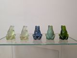 five glass frogs sitting on top of a glass shelf