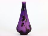 un vase violet orné de feuilles noires sur fond blanc
