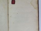 an open book with a wax stamp on it sitting on a table