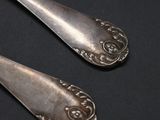 pair of silver spoons on a black surface with a black background