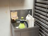 a sink in the corner of a kitchen with a shelf above it