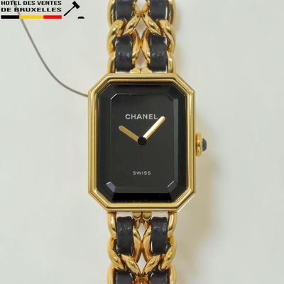une montre noire et dorée, entourée d'une chaîne