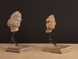two sculptures of a woman ' s head and a man ' s head on a wooden table