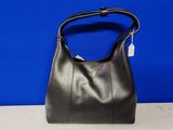 un sac à main en cuir noir posé sur une table, sur fond bleu