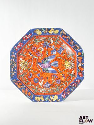 an orange and blue plate with flowers and birds on it