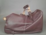 brown leather duffel bag with strap and handles on grey background