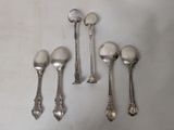 six spoons and a spoon rest on a white surface
