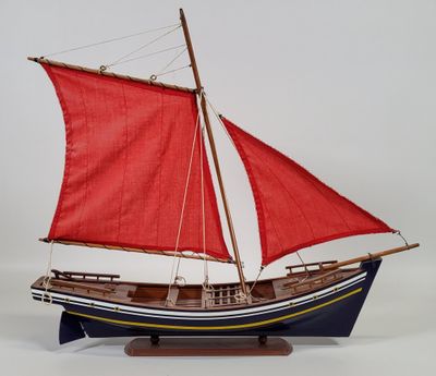 wooden model of a sailboat with red sails on a white background