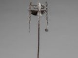 sculpture of a bird perched on a branch with a chain around its neck