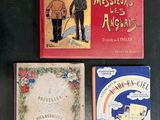 three children ' s books are sitting on a black surface