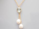 un collier en or orné de deux perles et d'une topaze bleue