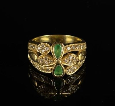 a close up of a gold ring with green and white stones