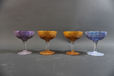 four wine glasses are lined up in a row on a gray surface