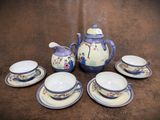 a tea pot and four cups and saucers on a table