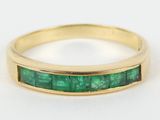 a close up of a gold ring with emerald stones