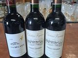 Trois bouteilles de vin sont posées sur une table, accompagnées d'une étiquette de prix