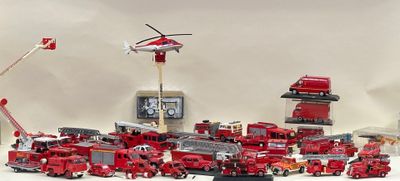 de nombreux camions de pompiers miniatures et un hélicoptère posés sur une table
