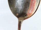 a silver spoon with a spoon handle on a white surface