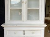une armoire blanche avec une porte vitrée au milieu d'une pièce
