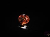 a close up of an orange diamond on a black surface