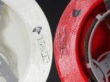 a close up of a red and white helmet and a white helmet