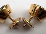 two pairs of gold cufflinks on a white surface