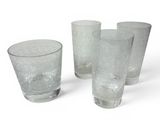quatre verres posés les uns à côté des autres sur une surface blanche