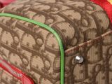 a brown and green bag with a red handle