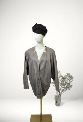 grey shirt on a mannequin stand with a flower in a vase