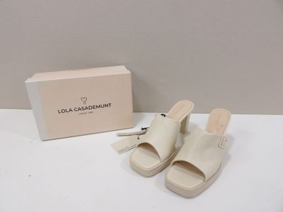 Les sandales blanches se trouvent à côté d'une boîte et d'une paire de chaussures