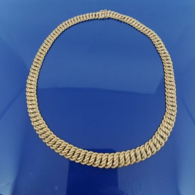 un gros plan d'un collier en or posé sur une surface bleue