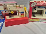 a small toy sewing machine in a box next to a box with a sewing machine in it