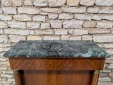 a wooden cabinet with a marble top in front of a brick wall