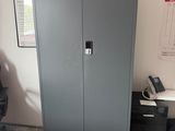 a metal cabinet in the corner of a room next to a desk