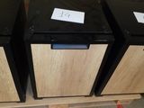 three black and wood refrigerators on a pallet in a warehouse