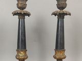 une paire de bougeoirs noirs et dorés sur socles, sur fond blanc