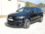 un SUV Audi noir garé devant un immeuble, sur un parking en gravier