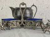 a silver tea pot and two blue cups on a table