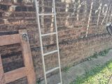 a ladder leaning against a brick wall next to a chair