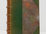 a brown and green book with a leather cover on a white surface
