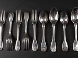 six spoons and six forks arranged in a row on a black surface