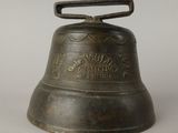 brass bell on a white surface with a black handle