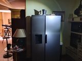 a refrigerator in the middle of a living room with a lamp on
