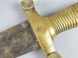 a close up of a gold colored sword on a white surface
