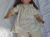 a doll that is laying on a bed with a white sheet