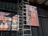 a man that is standing on a ladder in front of a picture