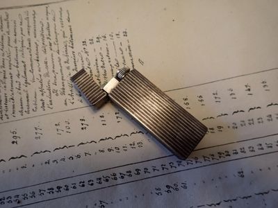 un briquet argenté posé sur un morceau de papier