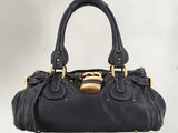 a black leather handbag with a gold buckle on the handle